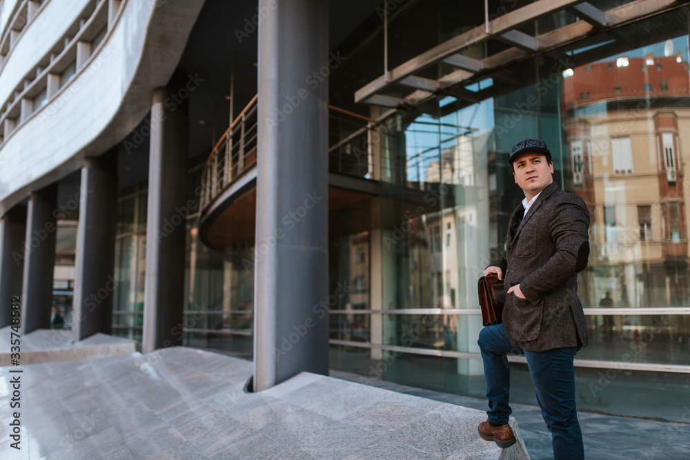 Young handsome caucasian businessman in front of company with bag in hand