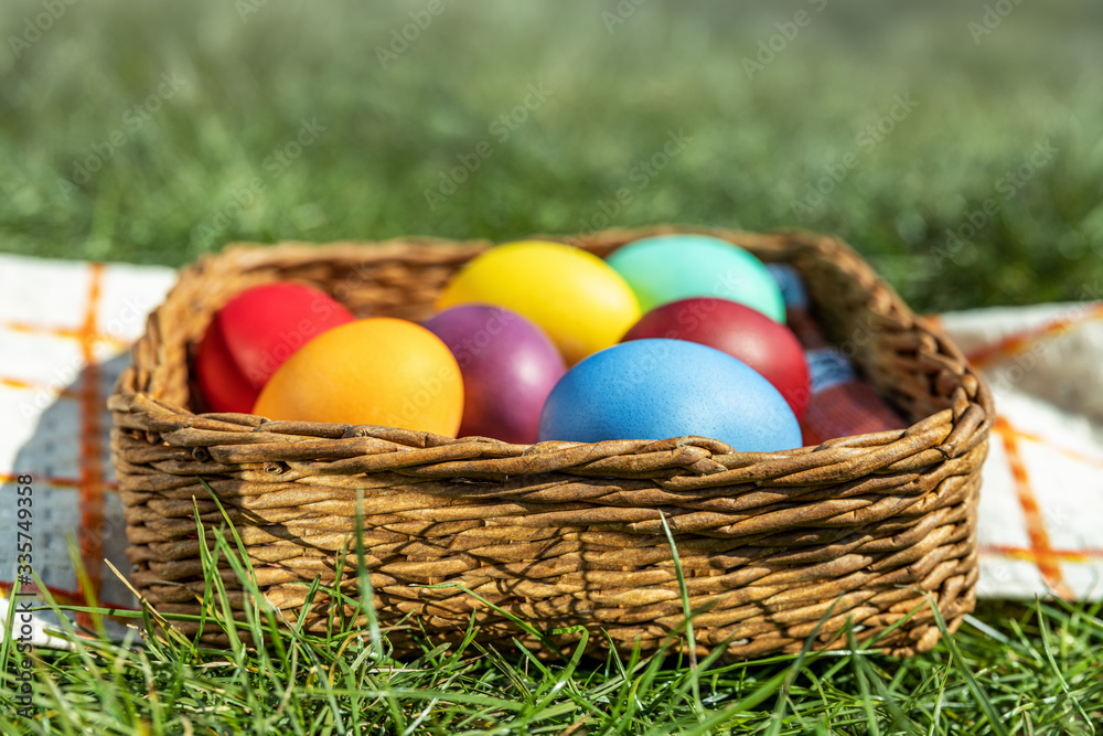 Multi-colored Easter eggs in a basket on the grass with a fog effect, the background is blurred, shallow depth of field, selective focus. Easter holiday concept Multi-colored Easter eggs in a basket on the grass with a fog effect, the background is blurred, shallow depth of field, selective focus. Easter holiday concept