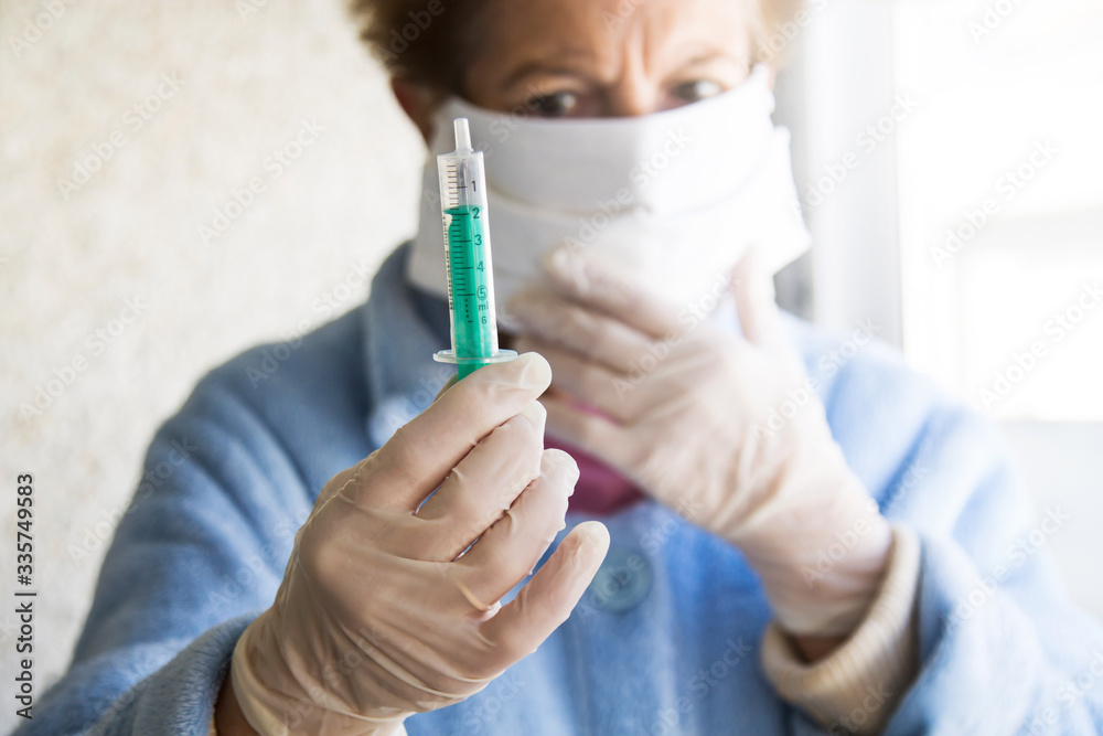 senior woman with mask and disposable medical gloves and syringe in one hand. concept of vaccine against infections and coronavirus senior woman with mask and disposable medical gloves and syringe in one hand. concept of vaccine against infections and coronavirus