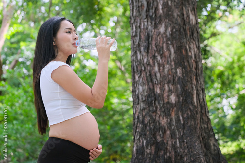 Pregnant women drink empty water for health, eating pregnant women outdoors, pregnant women in the park.