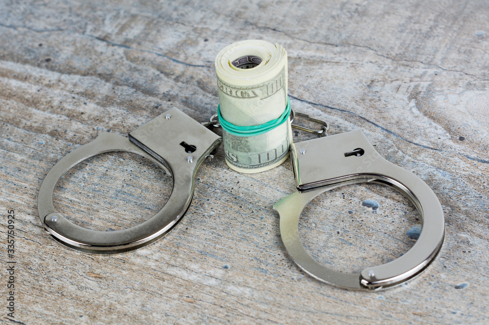 Handcuffs and usa dollar banknotes on wooden background Handcuffs and usa dollar banknotes on wooden background