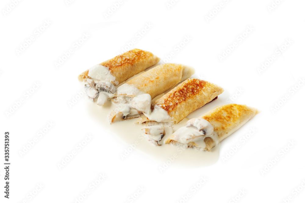 Thin pancakes with mushrooms and sauce isolated on the white Thin pancakes with mushrooms and sauce isolated on the white