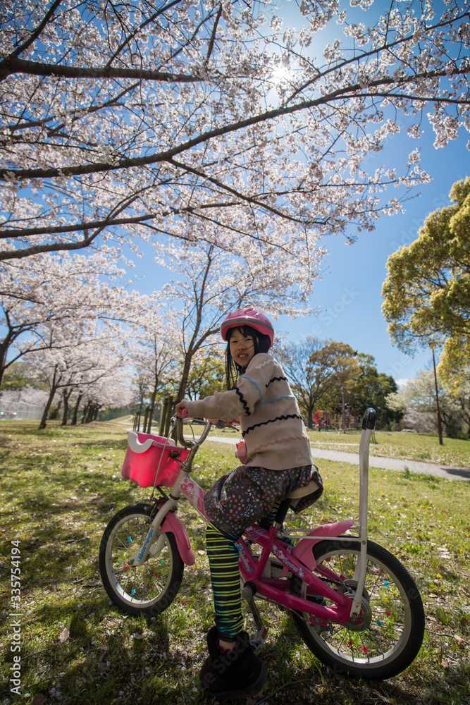 桜満開の公園で自転車を乗っている可愛い子供