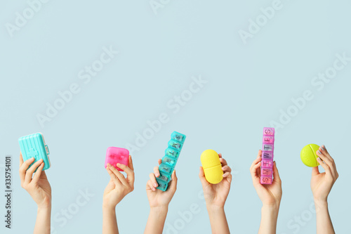 Female hands holding boxes with pills on color background