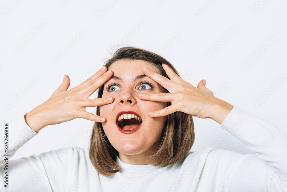 The woman covers her face with her hands and peeps The woman covers her face with her hands and peeps