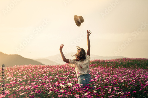 A girl throws her har in a field of colourful flowers.