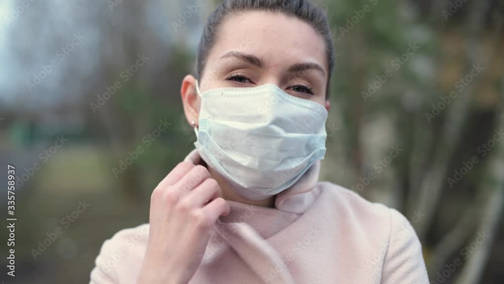 Close-up of a girl in a medical mask and coat on the street Close-up of a girl in a medical mask and coat on the street