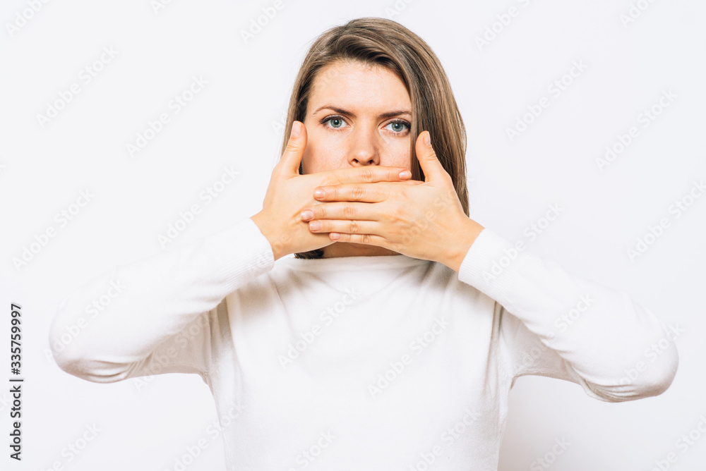 Successful stylish girl covers her mouth with her hands, isolated in the studio Successful stylish girl covers her mouth with her hands, isolated in the studio