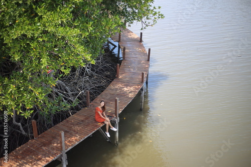 A woman sitting on a wooden walkway at Rak samae Bridge in Rayong, Thailand photo