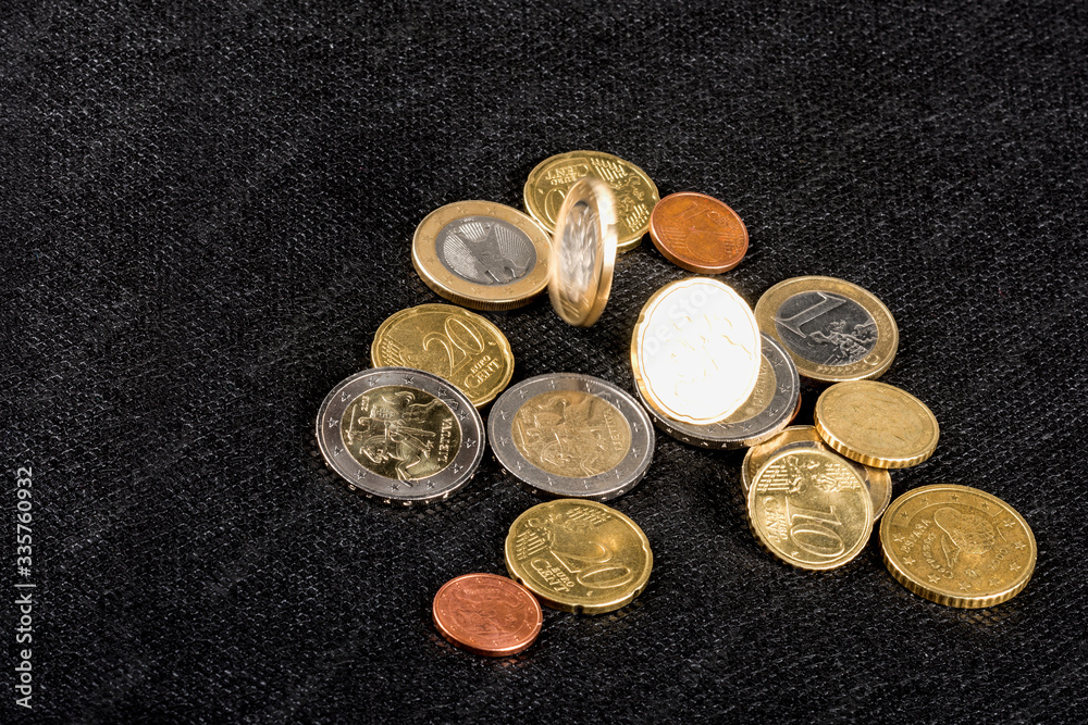 Euro coins falling and lying, on the black background; economics, consumption concept