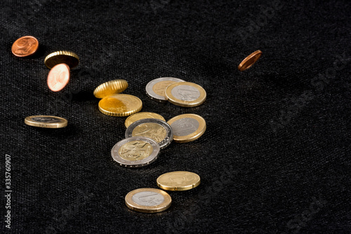 Euro coins falling and lying, on the black background; economics, consumption concept