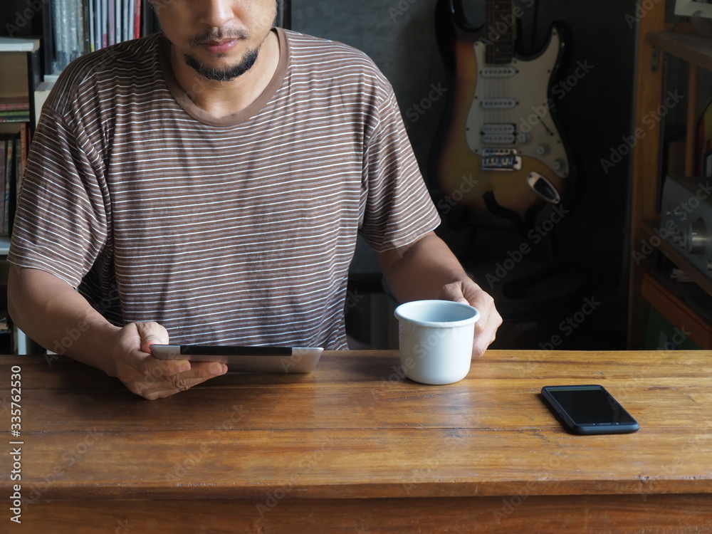 A man working with a tablet at home in front of the bookshelf A man working with a tablet at home in front of the bookshelf