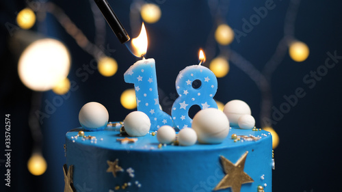 Birthday cake number 18 stars sky and moon concept, blue candle is fire by lighter. Copy space on right side of screen. Close-up photo