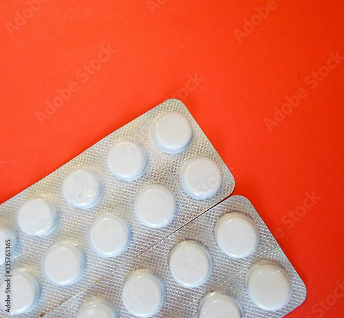 white pills on a red background. snow-white round antibiotics against viruses. photo