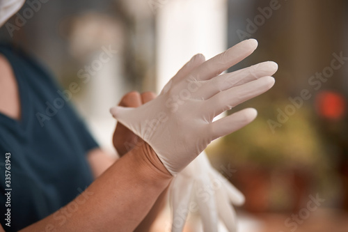 Female surgeon or nurse wearing a sterile suit putting on sterile rubber gloves to perform a surgery, Hand wearing a surgical gloves before starting the operation, Step by step procedures.