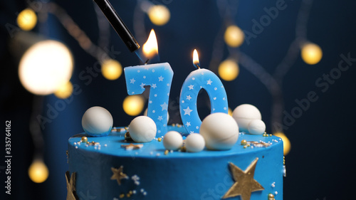 Birthday cake number 70 stars sky and moon concept, blue candle is fire by lighter. Copy space on right side of screen. Close-up