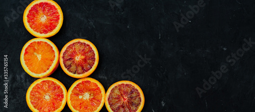Organic Raw Red Blood Oranges in a rows on a black background. Copy space for text. Banner