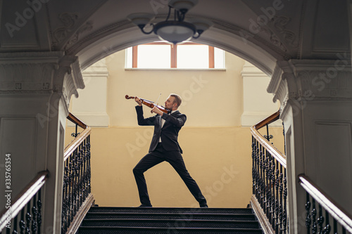 elegant talented professional violinist performing classical music, handsome guy in formal suit holding violin. classical music and instruments concept