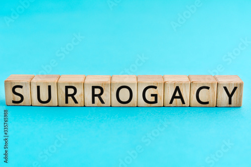 Surrogacy - word from wooden blocks with letters, a surrogate mother surrogacy concept, blue background photo