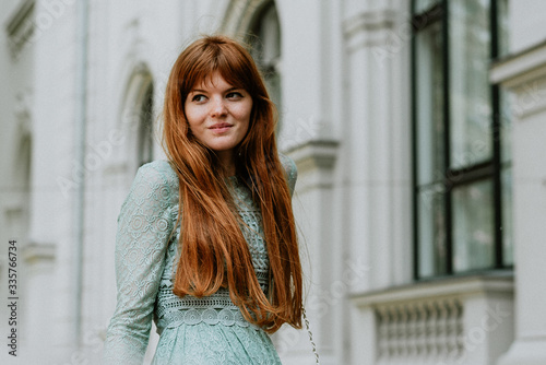Stylish urban young redhair woman in a fashionable green dress posing in the street. European modern cute model girl enjoys a walk in the city. Spring fashion. Free Download Stylish urban young redhair woman in a fashionable green dress posing in the street. European modern cute model girl enjoys a walk in the city. Spring fashion. - GFXLoad