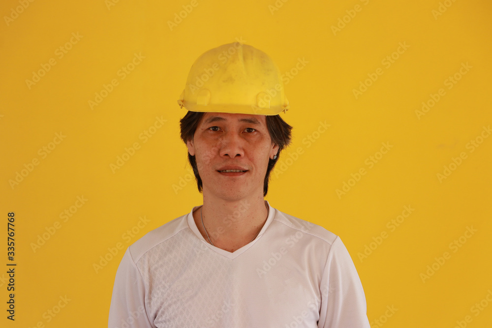 Male civil engineer with yellow helmet and wear white T-shirt on yellow background.