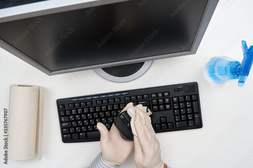 concept of cleaning or disinfecting the office - a businessman cleans the workplace, computer, desk, uses a spray gun and paper napkins. Cleaning surfaces from microbes, viruses and dirt. concept of cleaning or disinfecting the office - a businessman cleans the workplace, computer, desk, uses a spray gun and paper napkins. Cleaning surfaces from microbes, viruses and dirt.