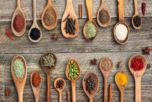 Spices and herbs in old wooden spoons on old wooden board