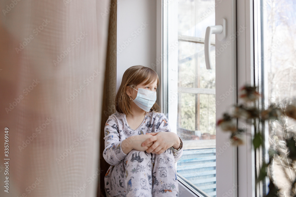 Illness child on home quarantine. Girl in protective medical masks sits on windowsill and looks out window. Virus protection, coronavirus pandemic, prevention epidemic.
Illness child on home quarantine. Girl in protective medical masks sits on windowsill and looks out window. Virus protection, coronavirus pandemic, prevention epidemic.