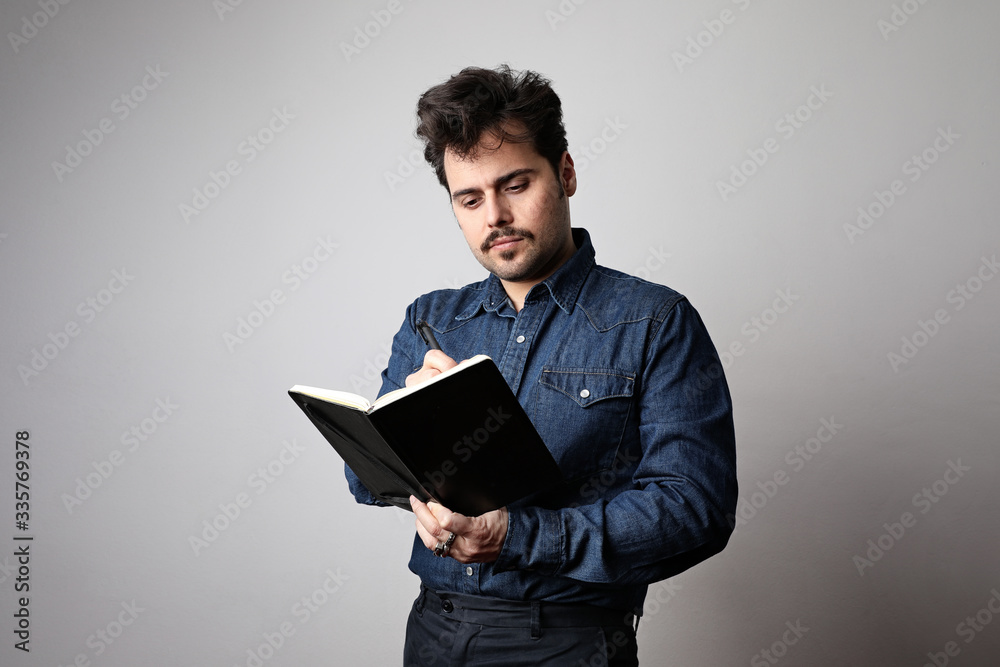 Modern young man hipster with a book and wearing a stylish denim shirt. Attractive guy in fashionable clothes.
