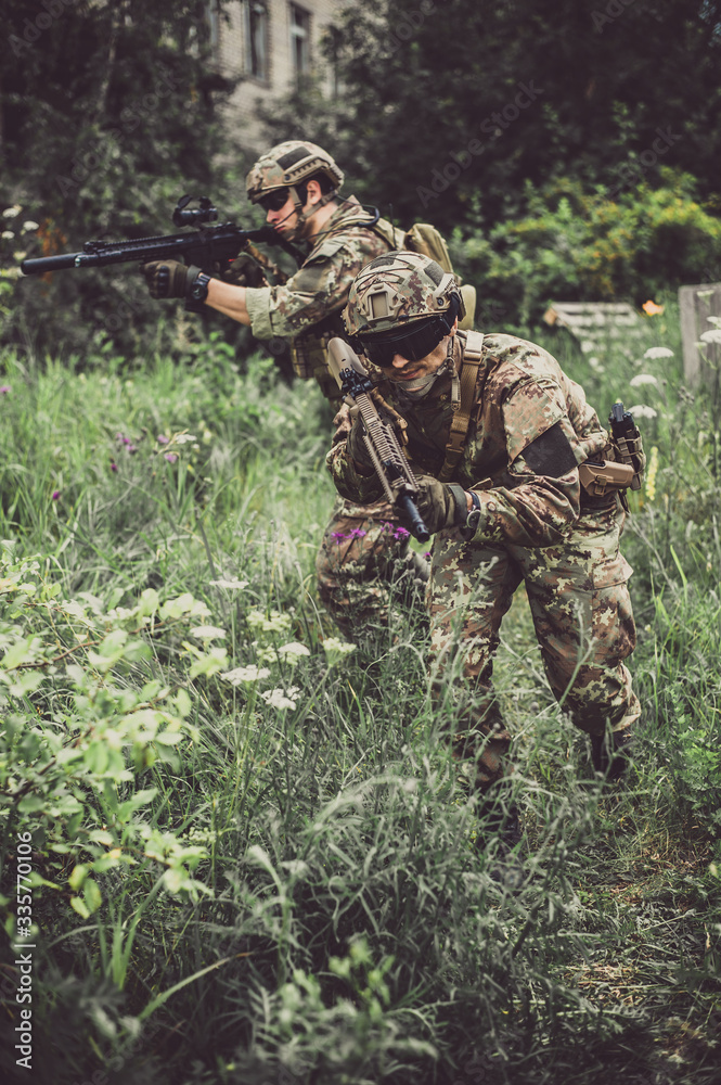 Two men in military camouflage vegetato uniforms with automatic assault rifles