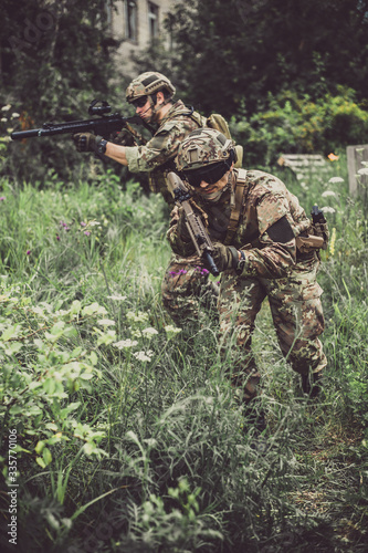 Two men in military camouflage vegetato uniforms with automatic assault rifles