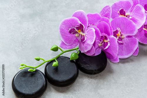 Thai Spa. Hot stones setting for massage treatment and relax on blackboard with copy space. Orchid flower with black stones pile for spa therapy. Lifestyle Healthy