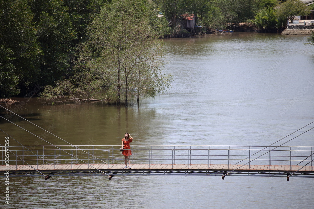Fototapeta premium A woman standing on a wooden walkway at Rak samae Bridge in Rayong, Thailand