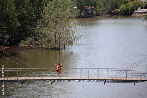 A woman standing on a wooden walkway at Rak samae Bridge in Rayong, Thailand photo