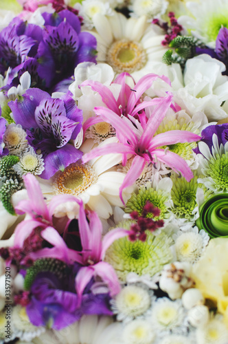 Pink lilies and other close-up flowers. The background is made of fresh flowers. © Olha