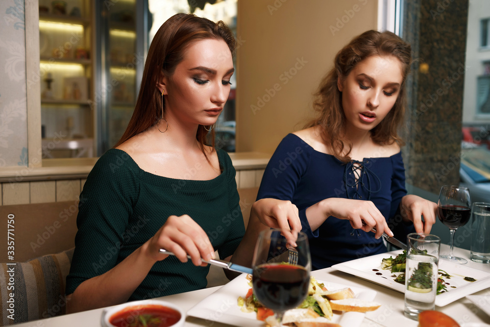 Two young successful women are having dinner in a restaurant and talking