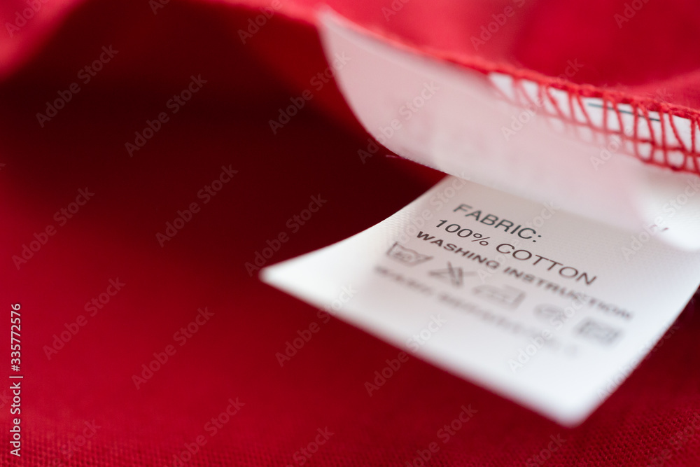 Fototapeta premium White laundry care washing instructions clothes label on red cotton shirt