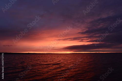 Sun flare in the cloudy sky at sunset on the horizon over water lake