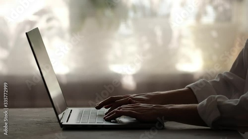Close up plan of opening laptop and typing. Silhouette and low key shot. Working at home and freelance concept. Typing hads in low key on a window background.