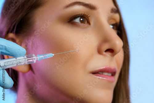 Beauty injection to attractive young girl in face. Cosmetology clinic, syringe in doctor hands