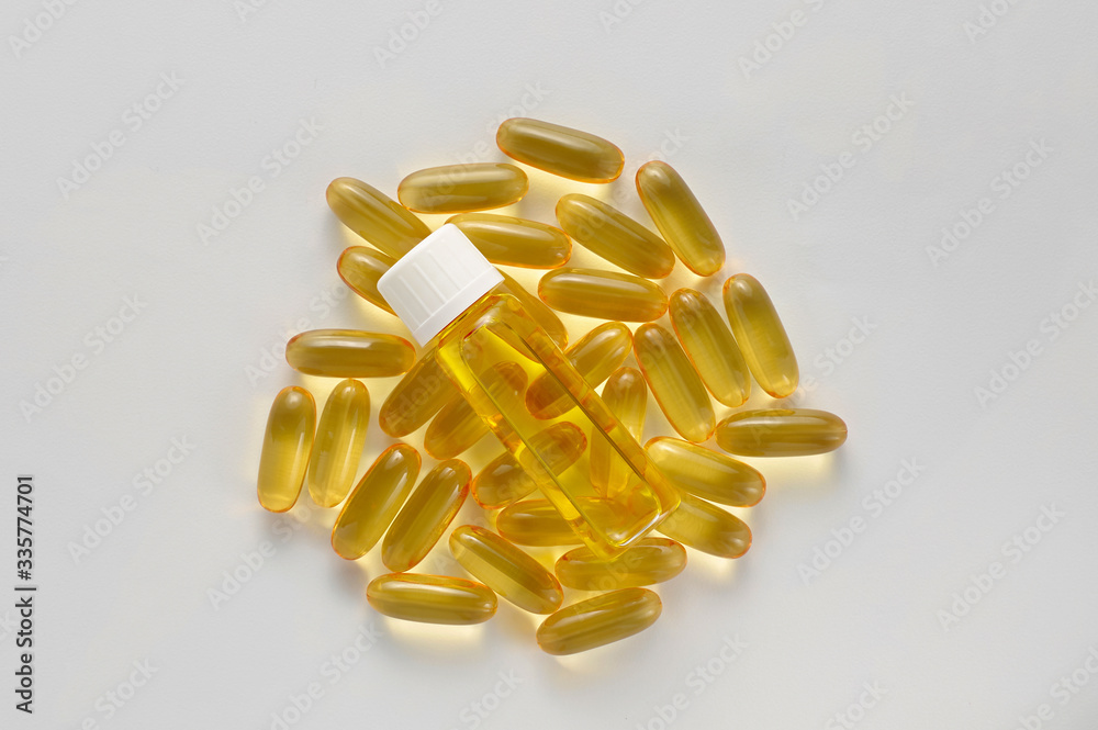 Glass bottle on heap pills of black cumin seeds essential oil Nigella Sativa on white background