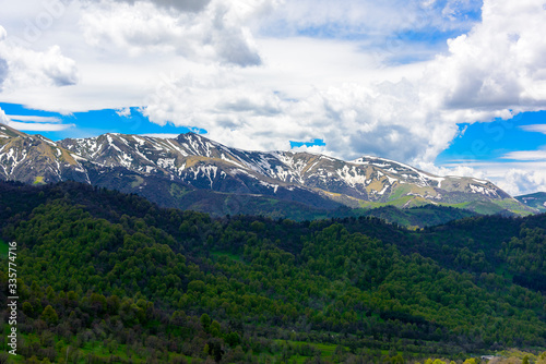 Beautiful mountain panorama with lush greens, blue skies, and puffy clouds