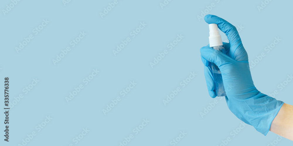 Fototapeta premium Hand in medical gloves with alcohol gel sanitizer on blue background