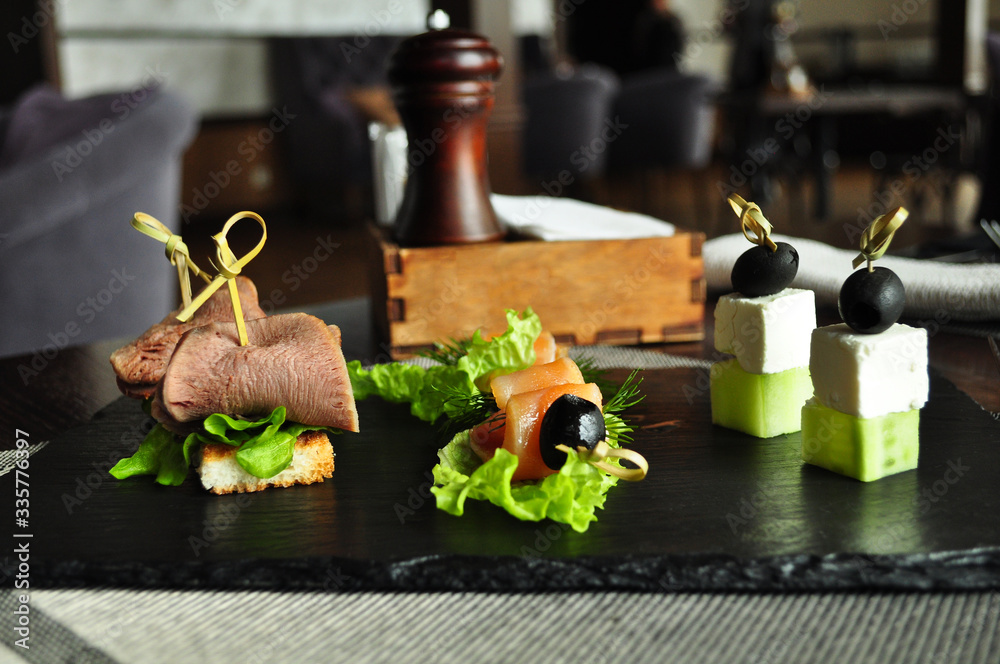 Assorted canapes, roast beef with salmon olives with cucumber and feta cheese on a board Assorted canapes, roast beef with salmon olives with cucumber and feta cheese on a board