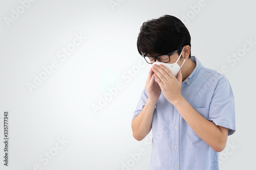 Asian man wearing surgical mask coughing and sneezing isolated from background, Covid19 human infection concept