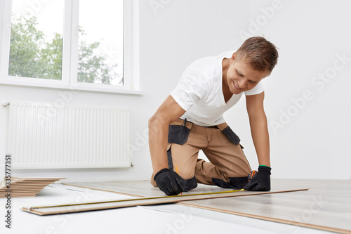 Professional craftsman puts laminate in a new apartment. The carpenter measures the cut line on the laminate. Repairing the wooden floor.