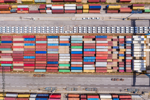 Corona virus lockdown, Rows of Shipping Containers and new Cars on hold due to Government guidelines impacting the Shipping and Auto industry, Top down aerial view.
