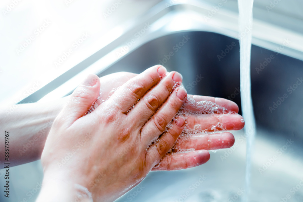 a young caucasian woman washing her hands with soap. Coronavirus pandemic COVID-19. Keeping hands clean is one of the most important steps to avoid getting sick and spreading germs to others. a young caucasian woman washing her hands with soap. Coronavirus pandemic COVID-19. Keeping hands clean is one of the most important steps to avoid getting sick and spreading germs to others.