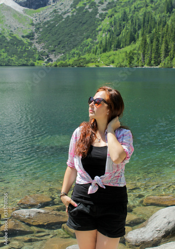 Tourist woman near the mountain lake Morskie Oko. Concept of travel and outdoor activities. Girl traveles the Tatra National Park, Zakopane, Poland. Carpathian mountains on background. photo