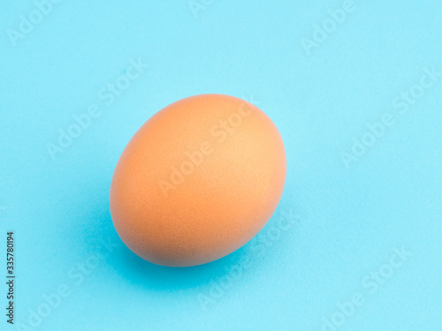 One brown chicken egg on a blue background. Healthy eating concept